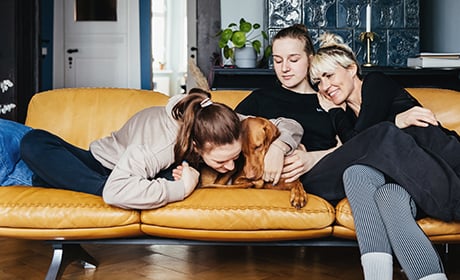 A mother and 2 daughters on the sofa with their dog